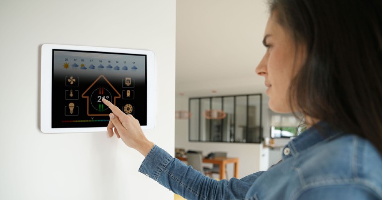 woman changing temperature of home using mounted tablet device