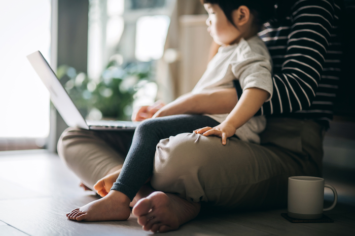 Child on parent's lap looking at a laptop