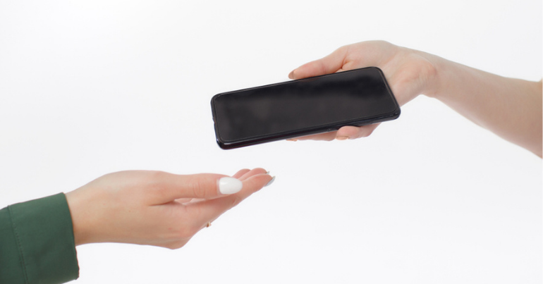 One hand handing another hand a mobile device