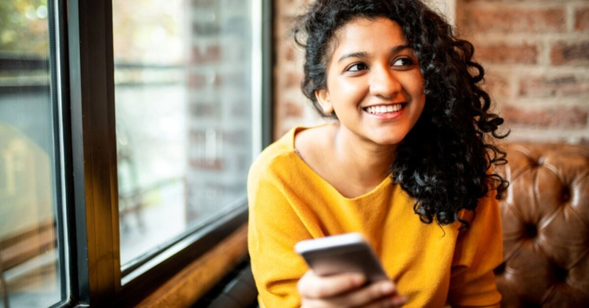 a person smiling and holding a phone