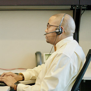 Customer Service Rep Man sitting down at a desk wearing a headset