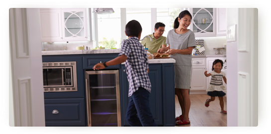 Family in Kitchen Woman standing in her kitchen, surrounded by three kids