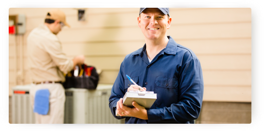 Technician & Repair Man Man in the foreground smiling at the camera and holding a pen and notebook and a repair man in the background
