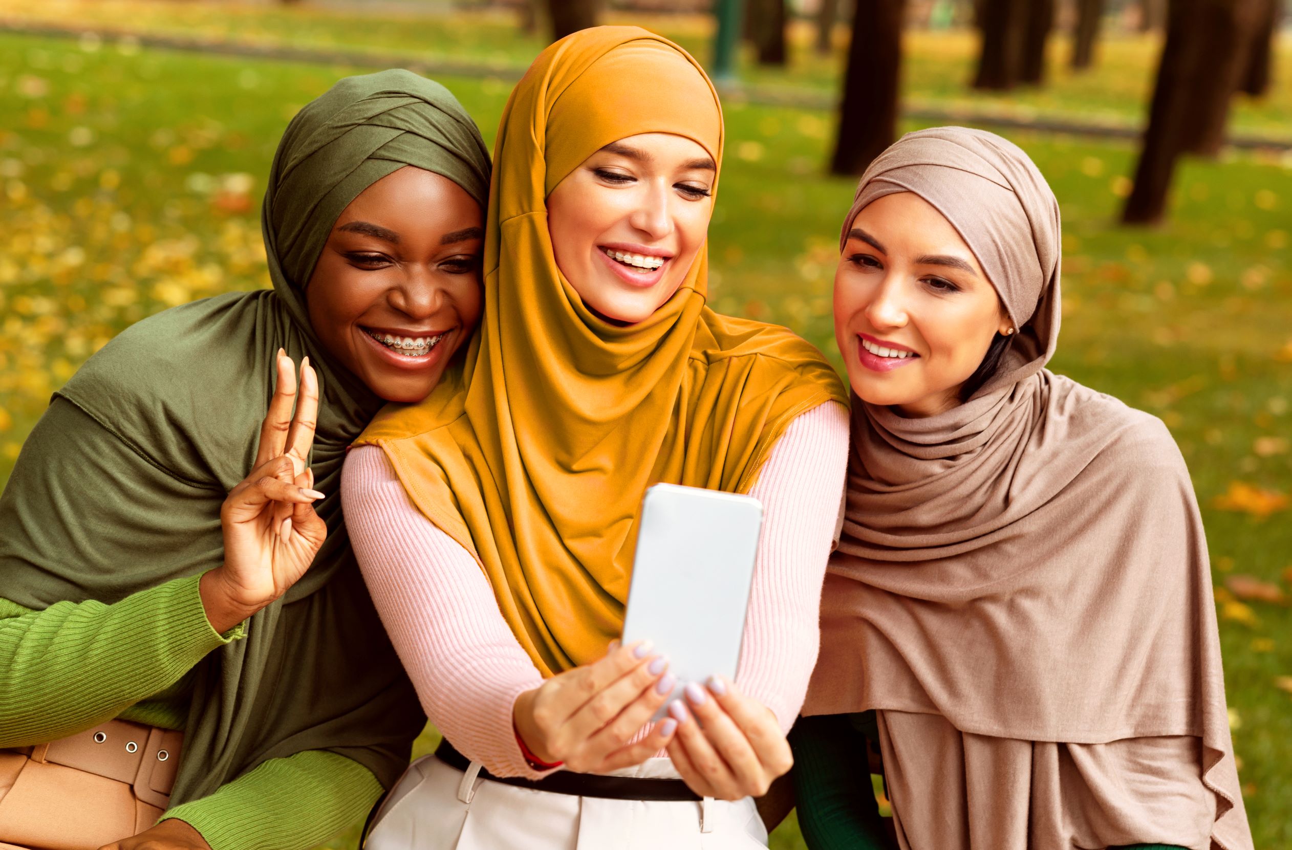 Women Taking Selfies Three women seating next to each other in the park taking a selfie.