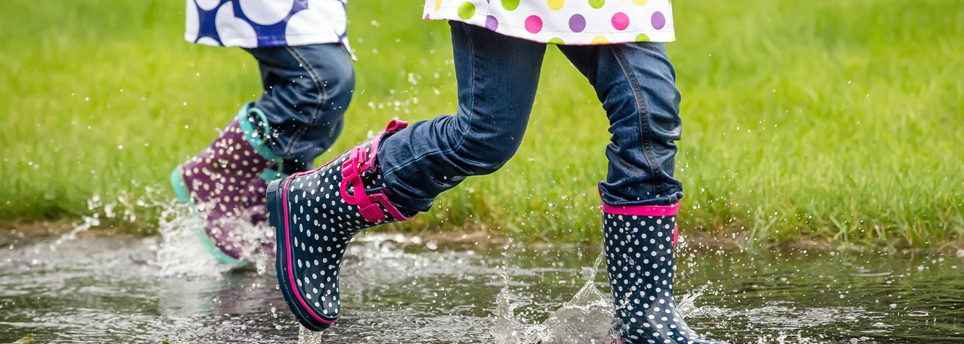 Kids jumping in a puddle splashing with rain boots