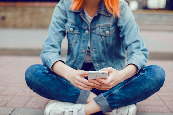 Close up of a woman seating down while she plays with her phone