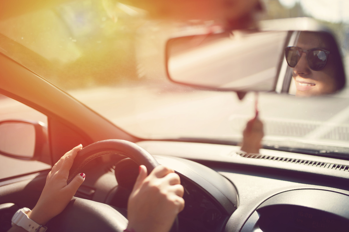 Woman driving with sunglasses looking in rearview mirror