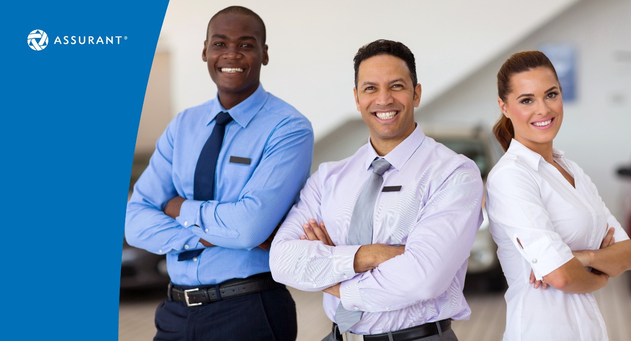 Three automotive dealership employees standing and smiling at camera