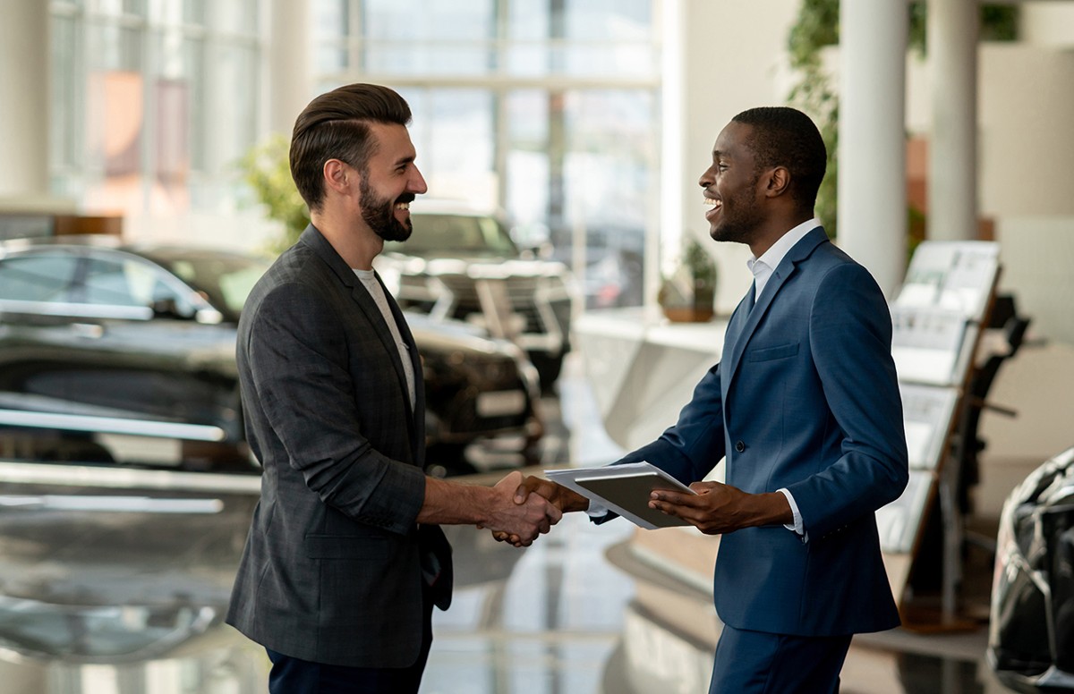 Two men in a auto dealership shaking hands