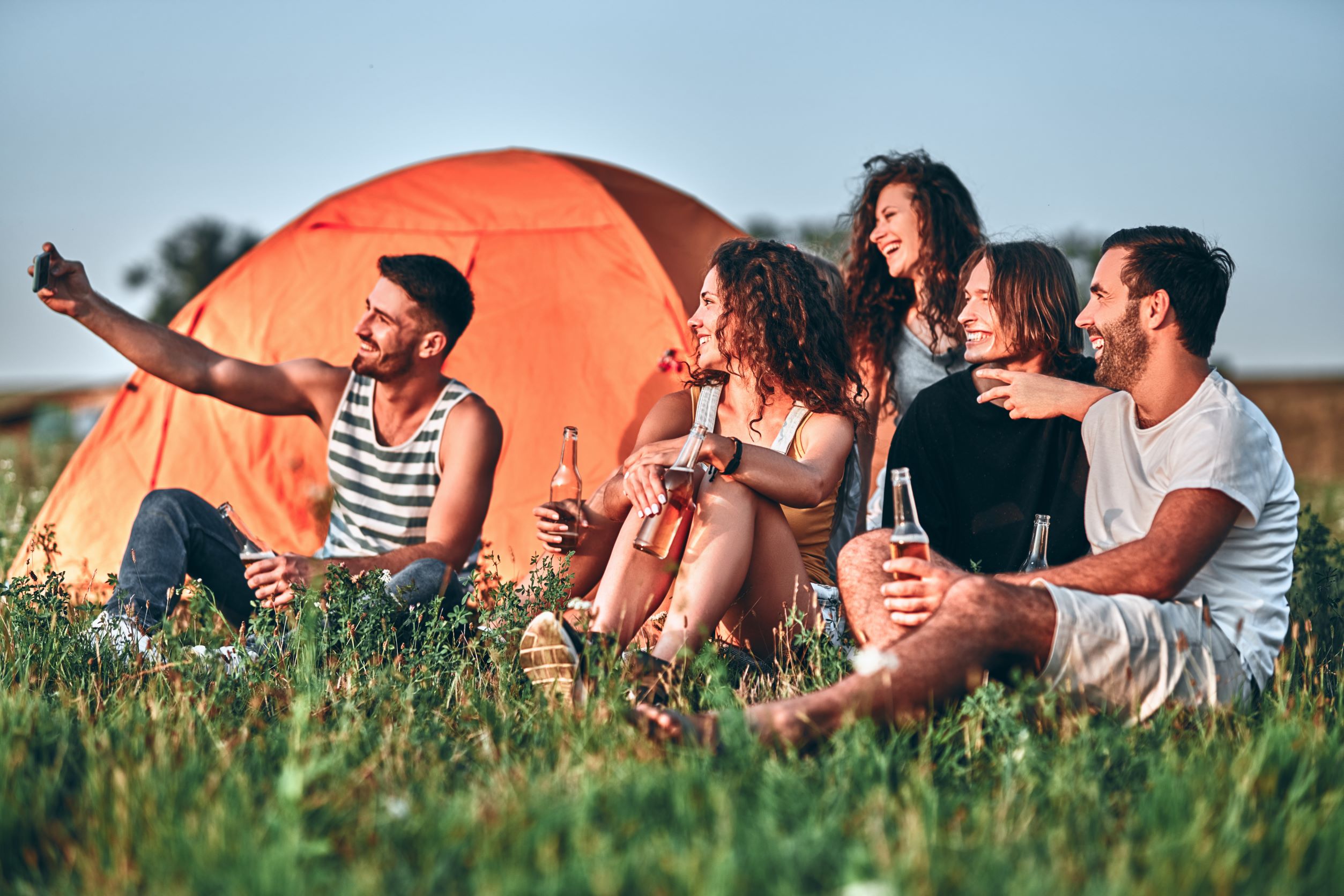 Group of five people camping, drinking beer and taking a selfie