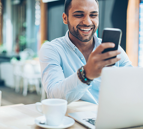 man smiling looking at phone in front of computer
