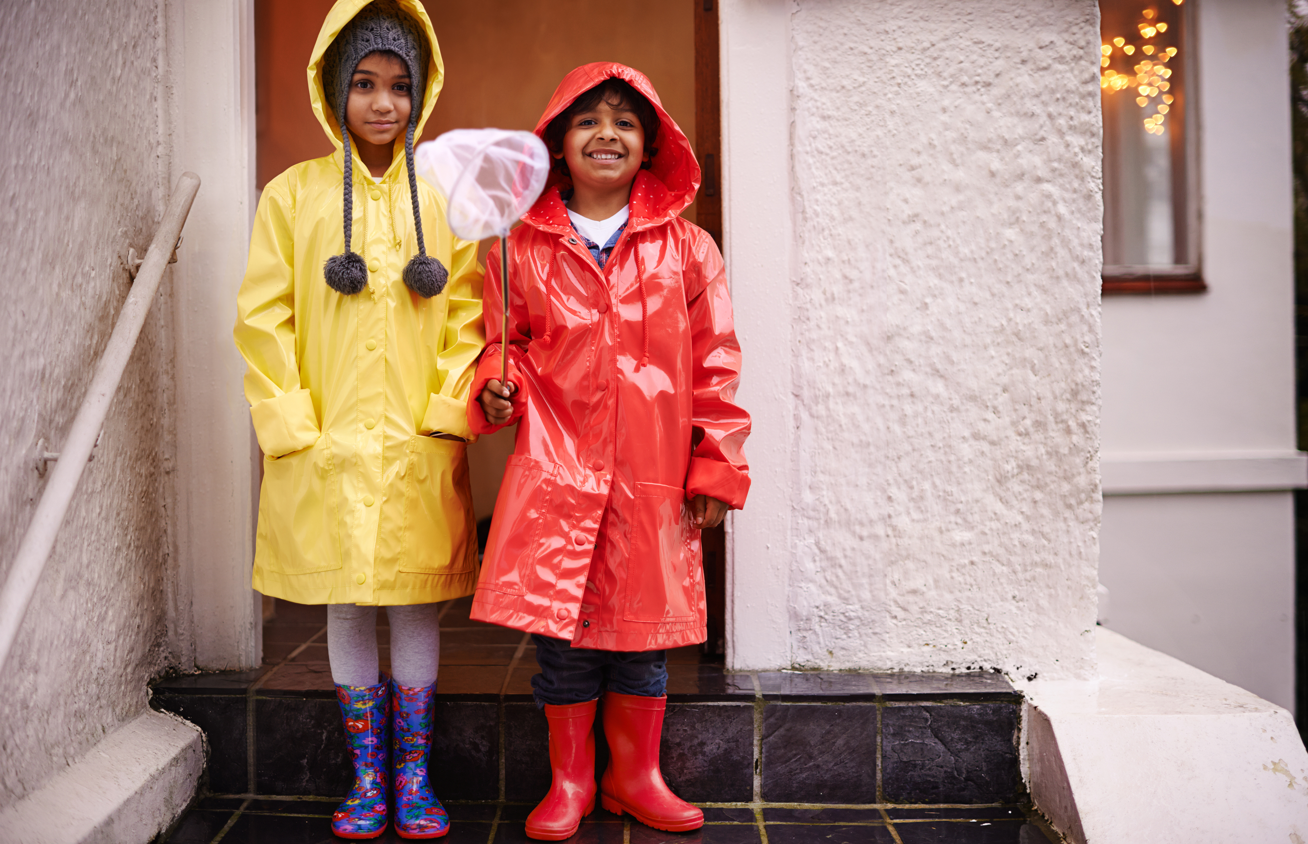 Flood Two children standing on their door step with raincoats and rain boots