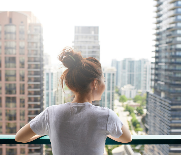 woman looking at city over terrace from apartment