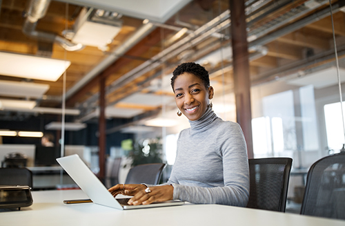 Property manager using her laptop Woman seating at a desk, using her laptop and smiling at the camera