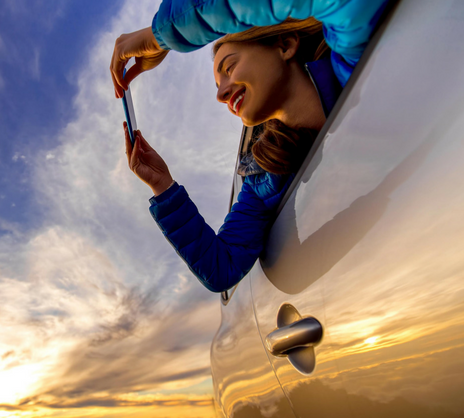 woman looking at phone in car sunrise